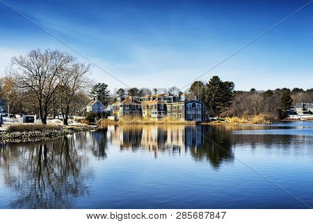 A Large Mansion Reflecting Off The Waters Of The Batson River In Kennebunkport Maine On A Cold Sunny