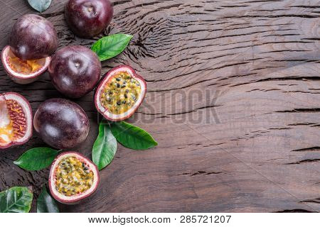 Passion fruits and its cross section with pulpy juice filled with seeds. Wooden background.