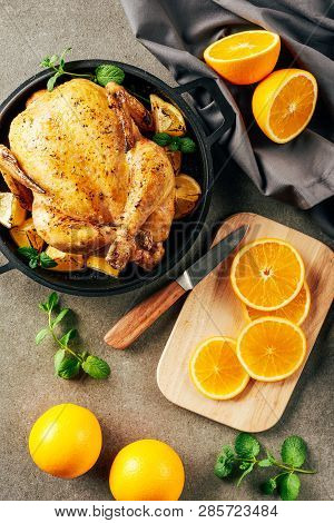 Cliced Oranges On Cutting Board With Knife And Fried Chicken In Griddle Pan