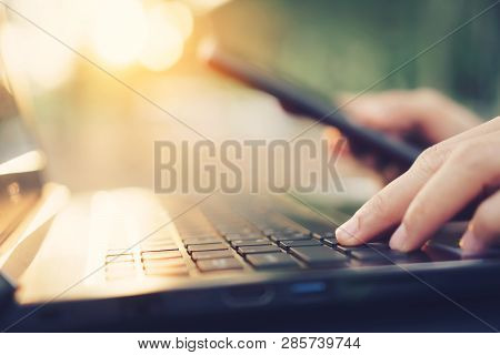Woman Hand Using Smart Phone And Laptop In Outdoor Nature Park And Sunset Sky With Bokeh Light Abstr
