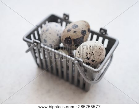 Several Small Spotted Quail Eggs Lie In A Small Gray Basket