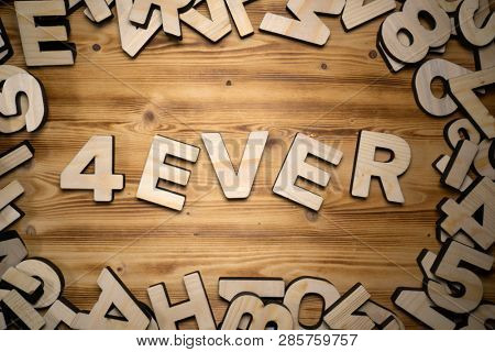 4EVER word made with block letters lying on wooden board