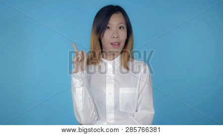 Young Asian Woman Posing Showing Hand Gesture Find Decision On Blue Background In Studio. Attractive