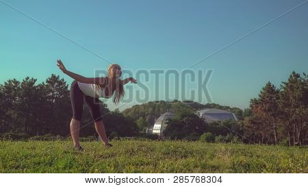 Woman Doing Stretching Exercises In The Park With Beautiful Nature Standing On The Meadow With Green