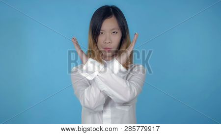 Young Asian Woman Posing Showing Hand Gesture Stopping Refuse On Blue Background In Studio. Attracti