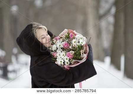 Happy Woman With A Bouquet Of Flowers On A Winter Background