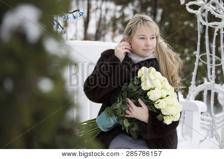 Woman In A Mink Coat With A Bouquet Of Flowers Sitting On A Bench