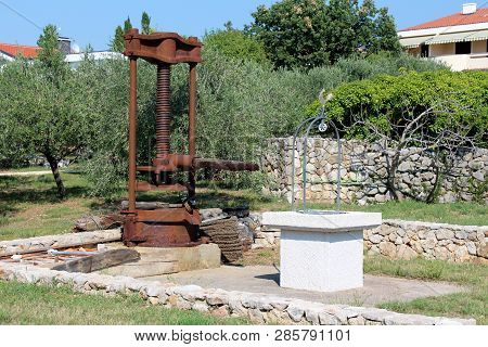 Large Rusted Metal Vintage Retro Olive Oil Press Machine Mounted On Concrete Foundation Next To Newl