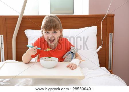 Little Child With Intravenous Drip Eating Soup In Hospital Bed