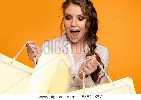 Picture Of Beautiful Smiling Young Woman In White Blouse Holding Cruft Bags After Shopping