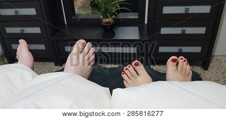Four Legs Man And Woman Under The Blanket In Bedroom