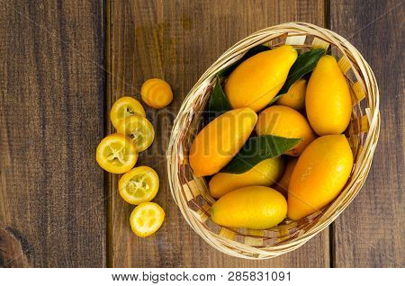 Ripe Sweet Orange Kumquats Fortunella In Wooden Basket.