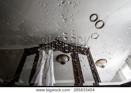 Blurred Pair Of Rings Is Leaning On A Glass Covered With Water Droplets On The Foreground. White Wed