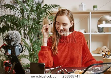 Eyebrows Modeling. Smiling And Young Blogger Wearing Red Sweater Modeling Her Eyebrows While Recordi