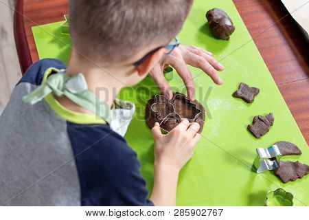 The Boy Squeezes The Shapes From The Molds On The Rolled Brown Dough. Pressed Shapes Are Next To Pre
