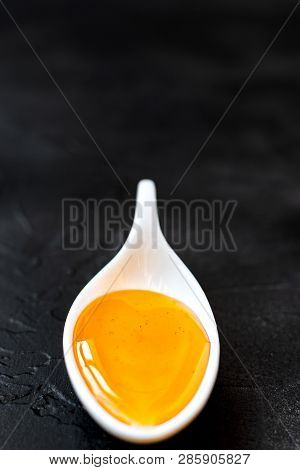 Ceramic Spoon With Honey, On A Textured Black Background.