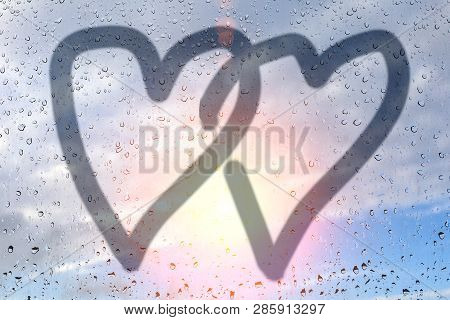 Picture Of Two Hearts On A Misted Glass. Glass Window With Raindrops Against The Blue Sky. Concept O