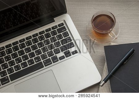 Laptop Work Area With Notebooks And Pens And Tea