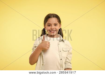 Good Quality. Kid Girl Shows Thumb Up Gesture Recommends Yellow Background. Child Highly Recommend W