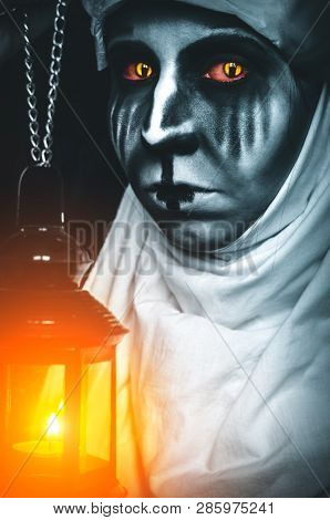 Portrait Of A Creepy Evil Nun With Lantern On Black Background. Vertical Poster For A Horror Movie A