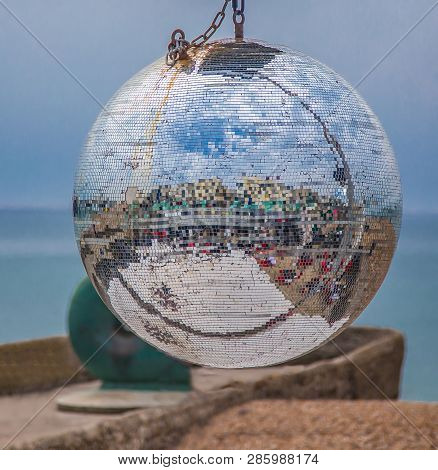 Mirrored Gitter Disco Ball With A Blue Background. Abstract Colours And Shapes Refelected In The Sil