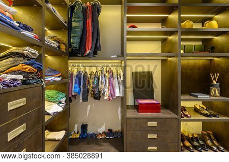 Large luxury men's wardrobe with different clothes shoes and accesories, front view