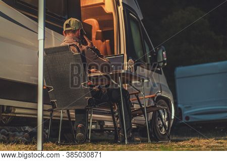 Caucasian Men Working On His Laptop Computer Next To His Rv Motorhome. Making Business Phone Call Wh