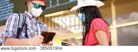 Man And Woman Hold Agaist Airport Background Passport With Plane Ticket Portrait. Trip After Covid 1