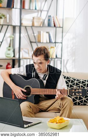 Talented Creative Teenge Boy Watching Tutorial On Laptop When Learning How To Play Guitar Or Playing