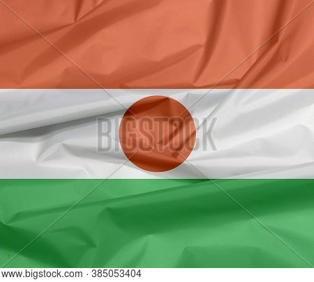 Fabric Flag Of Niger. Crease Of Nigerien Flag Background, Orange White And Green; Charged With An Or
