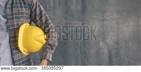 Construction Worker Holding Safety Helmet Yellow On Cement Wall Background With Copy Space
