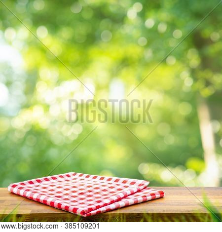 Red Checked Tablecloth On Wood With Blur Green Bokeh Of Tree Background.summer And Picnic Concepts.d