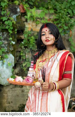 Portrait Of Beautiful Indian Girl Wearing Traditional Indian Saree, Gold Jewellery And Bangles Holdi