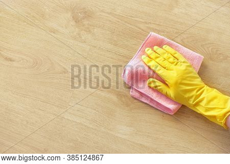 A Man's Hand In A Yellow Rubber Glove Oil Polishes The Wooden Surface Of The Table, The Floor With A