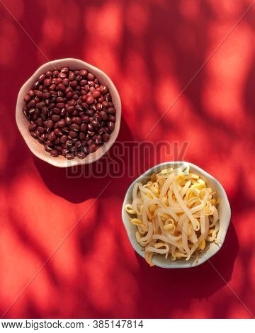 Red Mung Beans And Beansprouts In The Bowls On Red Background. Healthy Eating, Vegan Food Concept. T