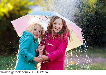 Kids With Colorful Umbrella Playing In Autumn Shower Rain. Little Boy And Girl In Warm Duffle Coat P