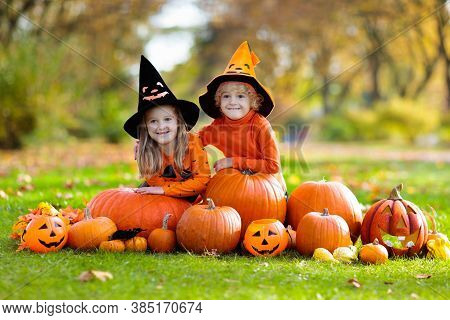 Kids Trick Or Treat On Halloween. Children In Black And Orange Witch Costume And Hat Play With Pumpk