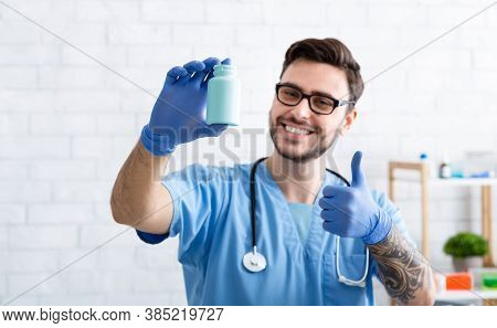 Happy Veterinarian Doc Showing Jar Of Pills And Making Thumb Up Gesture At Clinic, Space For Design.
