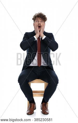 shocked businessman slapping his face, looking up and sitting on white background