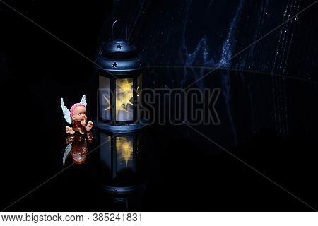 The Little Toy Angel, Small Lamp,  Black Background. Mysticism. Mystical Atmosphere. Esoteric Concep