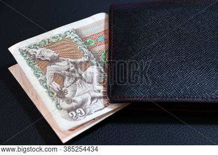 Seventy Five Of Banknote Currency Myanmar Kyats With Black Wallet On The Black Floor. It Is The Retr