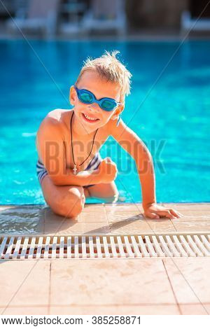Cute Happy Little Boy In Goggles Swimming In The Swimming Pool