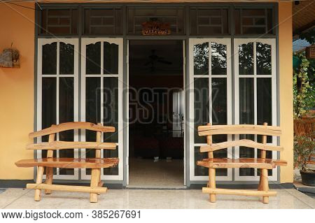 Wooden Open Door Of A Home. Front View Of A Wooden Front Door On A Yellow House With Reflections In 