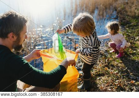 Father With Small Kids Collecting Rubbish Outdoors In Nature, Plogging Concept.