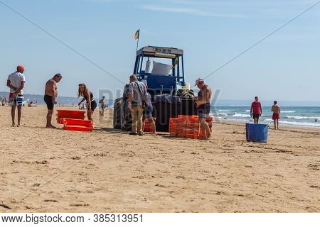 Costa Da Caparica, Portugal - September 10, 2020: An Artel Of Fishermen Trawls Fish From The Tourist