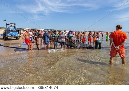 Costa Da Caparica, Portugal - September 10, 2020: An Artel Of Fishermen Trawls Fish From The Tourist