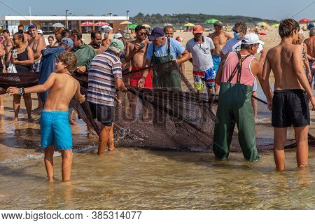 Costa Da Caparica, Portugal - September 10, 2020: An Artel Of Fishermen Trawls Fish From The Tourist