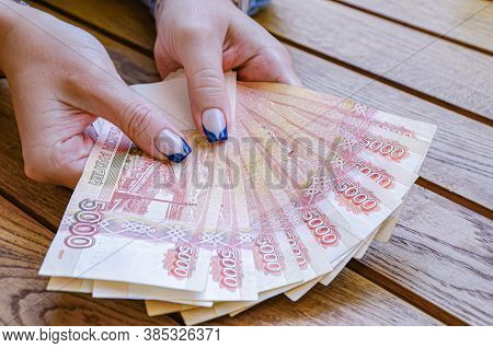 Female Hands With A Manicure Hold A Fan Of Five-thousandth Russian Ruble Bill On The Background Of A