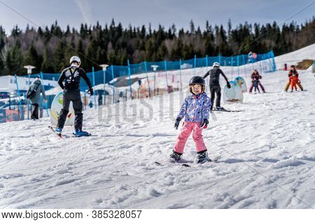Young happy skier girl learning how to ski on the green ski zone. Young skier having fun on ski slope, Bialka Tatrzanska, Tatry, Poland