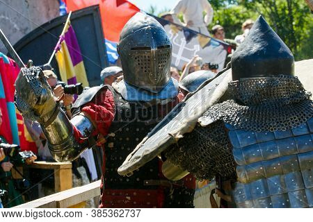 Knight Tournament. Medieval Restorers Fight With Swords In Armor At A Knightly Tournament